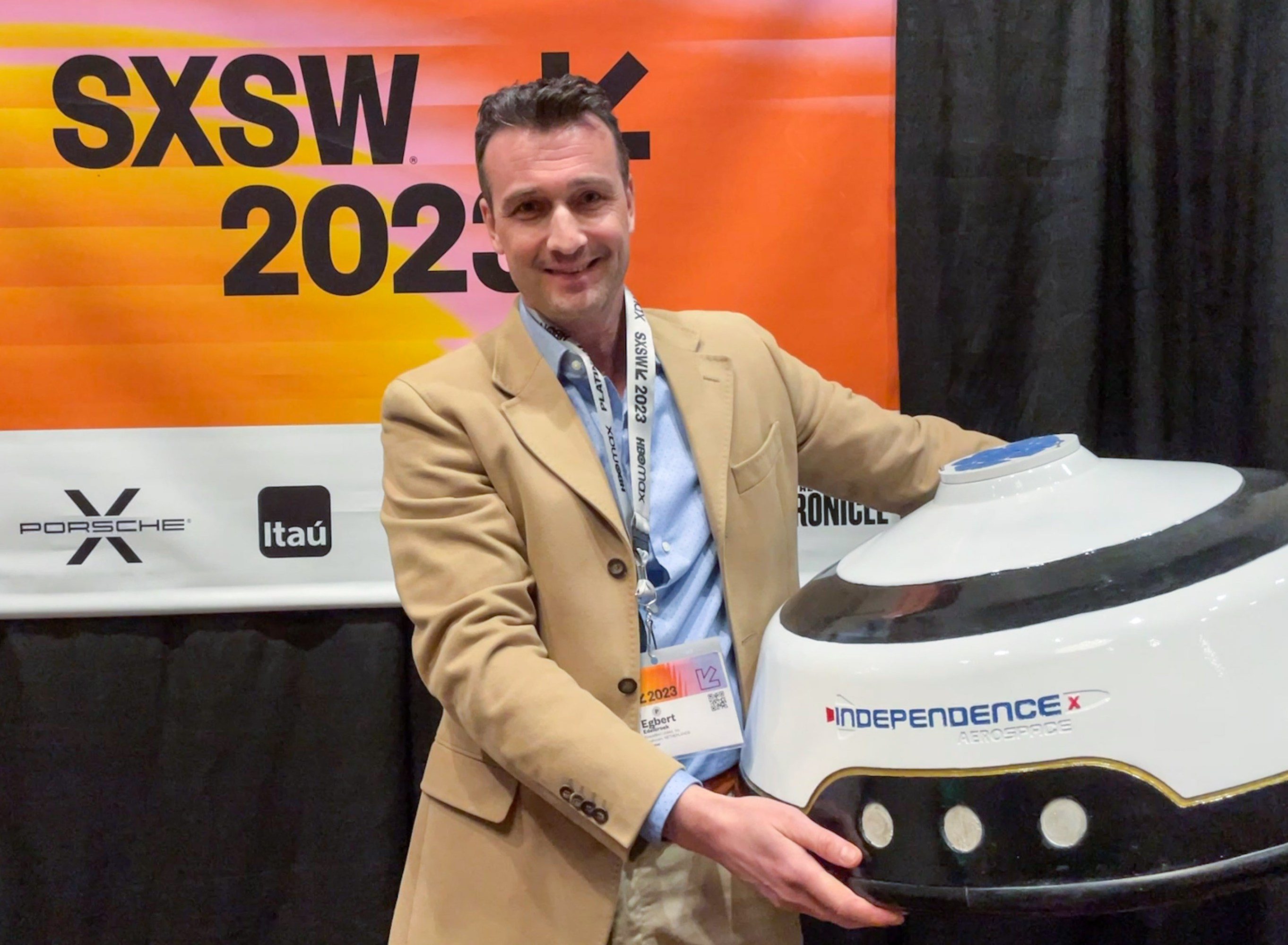 Edelbrook in front of a banner for SXSW holding the Independence Aerospace capsule