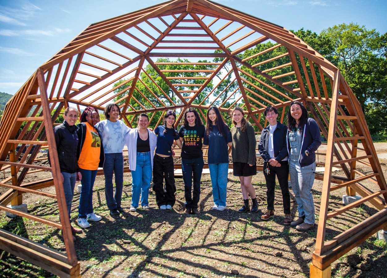 10 young women pose inside an open wooden dome