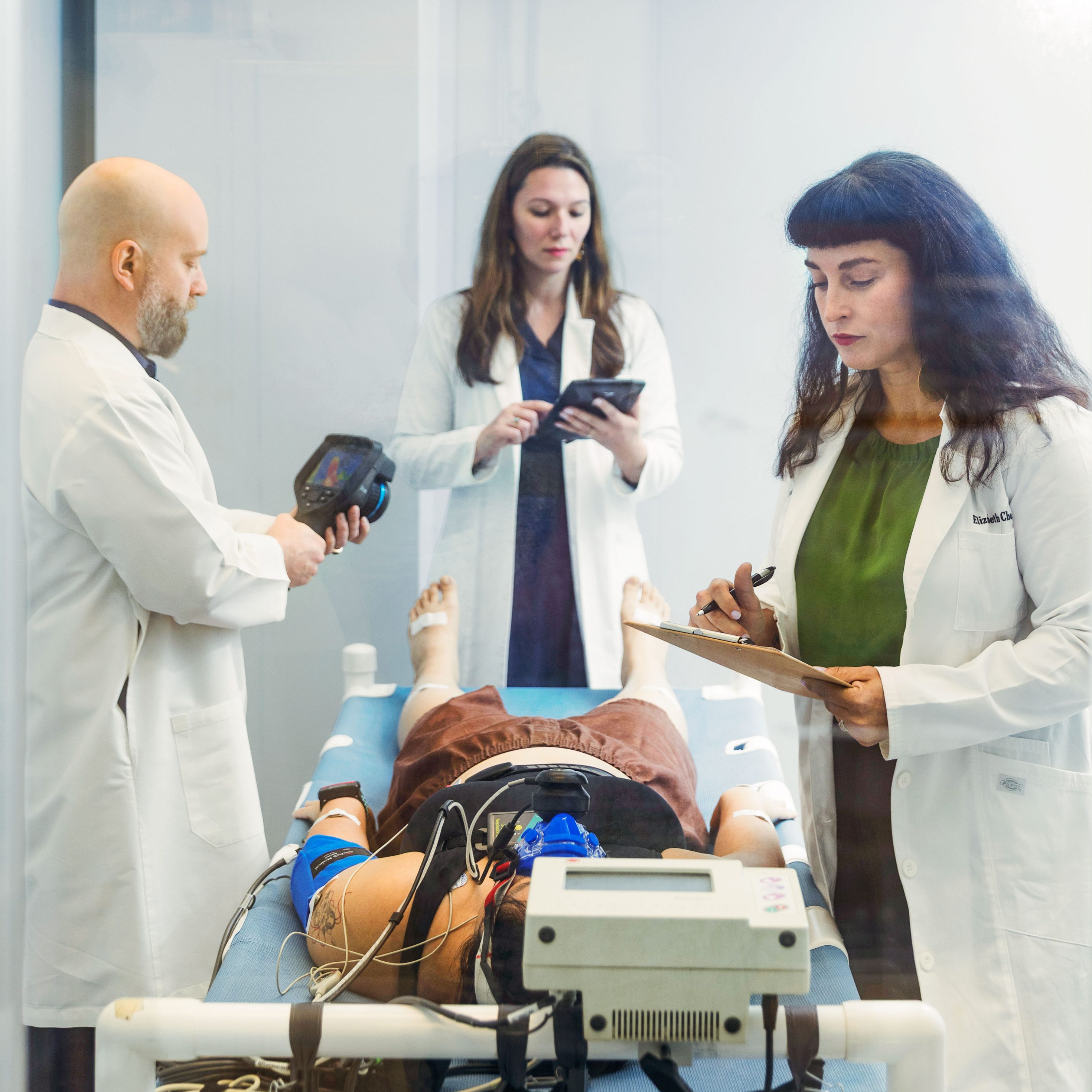 three medical team members make preparations around a person on a gurney