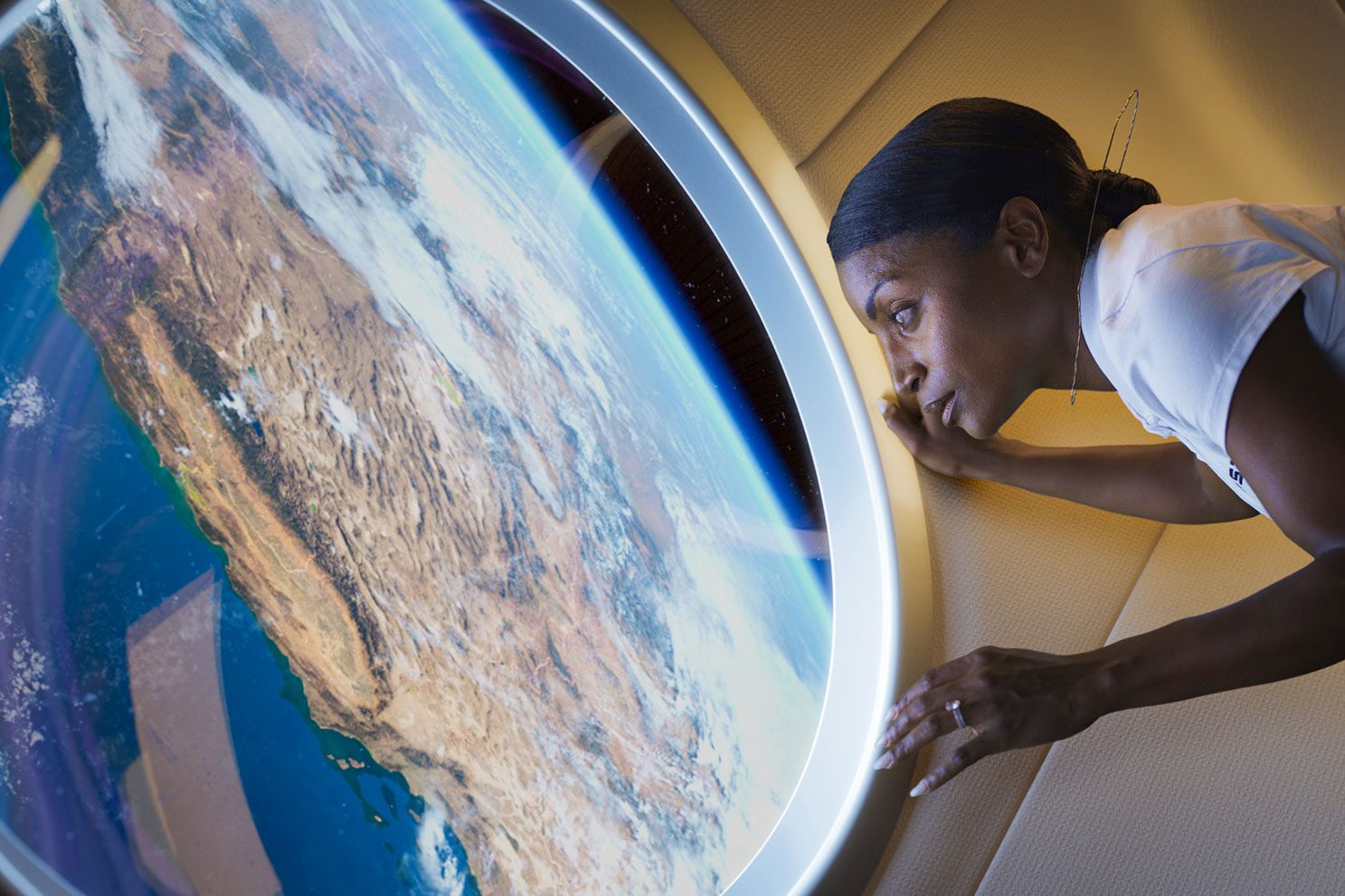 A person looks out the window of Haven-1 at the Earth.